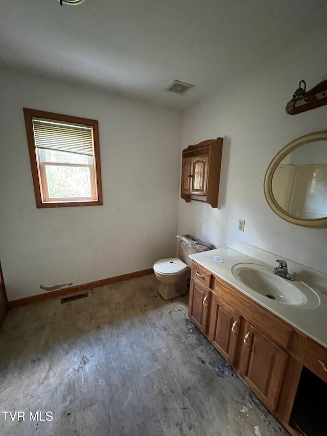 bathroom with toilet, vanity, and wood-type flooring