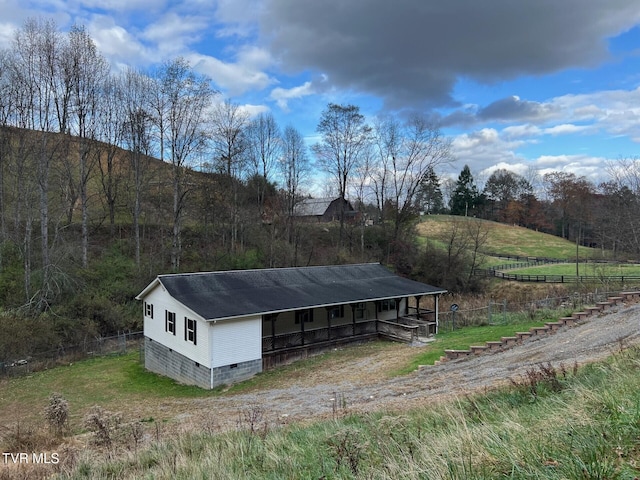 view of side of home featuring a rural view and an outdoor structure