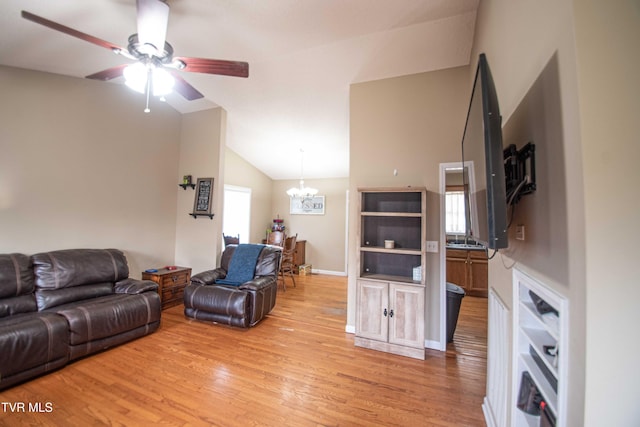 living room with light hardwood / wood-style floors, ceiling fan with notable chandelier, and lofted ceiling