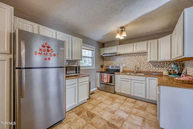 kitchen with a sink, white cabinetry, appliances with stainless steel finishes, tasteful backsplash, and dark countertops