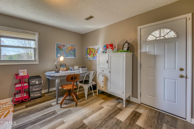 office space with baseboards, a textured ceiling, visible vents, and light wood-style floors