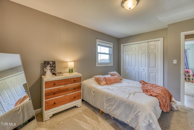 bedroom with a closet, light carpet, and baseboards