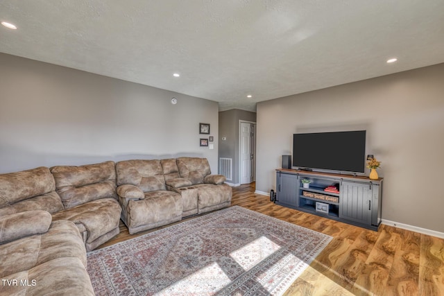 living room featuring visible vents, baseboards, light wood-style flooring, and recessed lighting