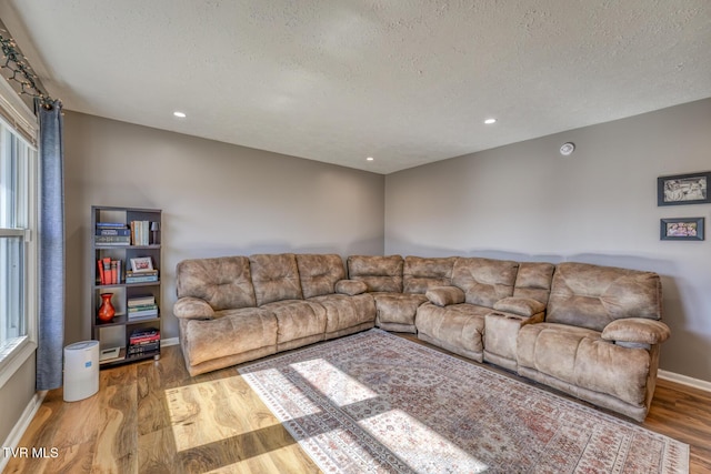 living room featuring light wood finished floors, baseboards, a textured ceiling, and recessed lighting