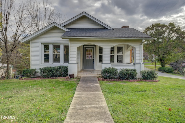 bungalow-style home with a front yard and covered porch