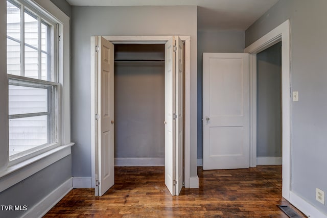 unfurnished bedroom featuring a closet and dark hardwood / wood-style flooring