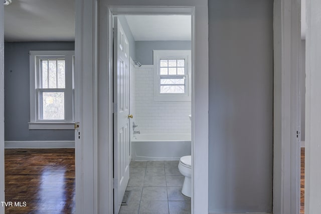 bathroom featuring hardwood / wood-style flooring, a healthy amount of sunlight, toilet, and tiled shower / bath