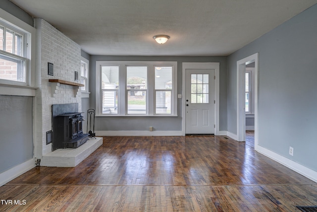 unfurnished living room featuring a wood stove, a textured ceiling, and dark hardwood / wood-style floors