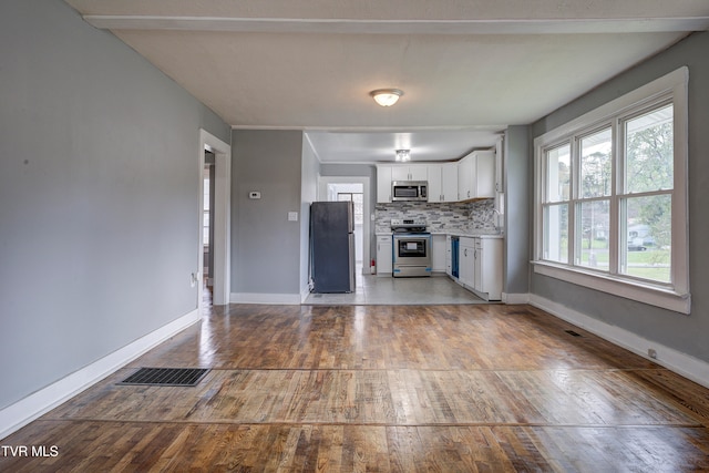 kitchen featuring hardwood / wood-style floors, white cabinetry, appliances with stainless steel finishes, and tasteful backsplash