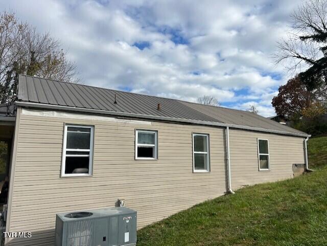 view of side of home with a lawn and central air condition unit