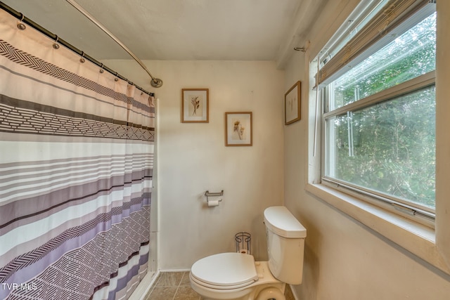 bathroom with a wealth of natural light, tile patterned flooring, toilet, and shower / bath combination with curtain