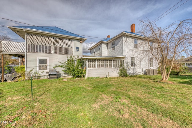 back of property featuring central AC unit, a sunroom, and a yard