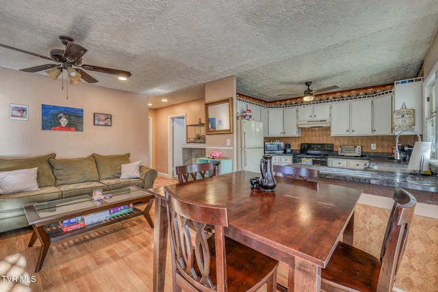 dining space featuring ceiling fan, a textured ceiling, sink, and light hardwood / wood-style flooring