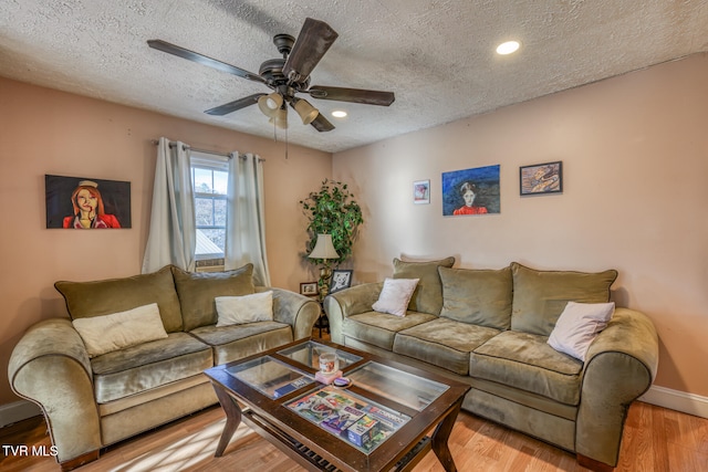 living room featuring hardwood / wood-style floors, ceiling fan, and a textured ceiling