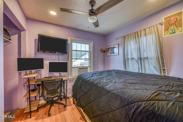 bedroom featuring cooling unit, a textured ceiling, ceiling fan, and light hardwood / wood-style flooring