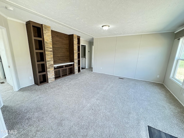 unfurnished living room featuring a textured ceiling, carpet flooring, and ornamental molding