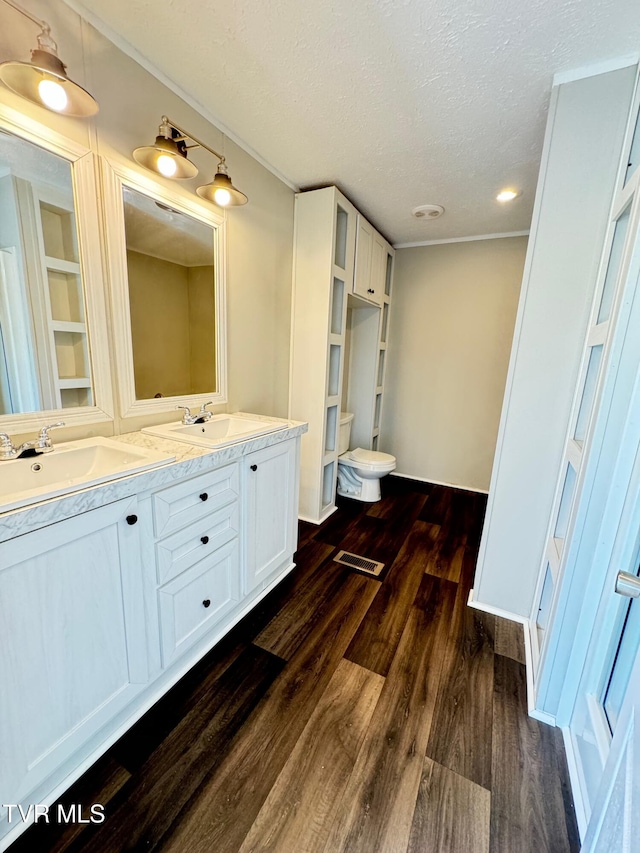 bathroom featuring hardwood / wood-style floors, a textured ceiling, toilet, and vanity