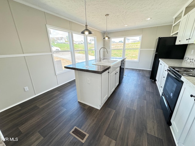 kitchen featuring black appliances, sink, an island with sink, and white cabinets