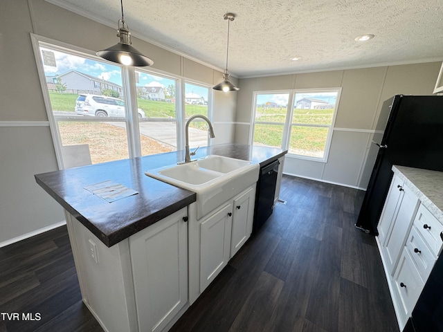 kitchen featuring a center island with sink, black appliances, sink, pendant lighting, and white cabinetry