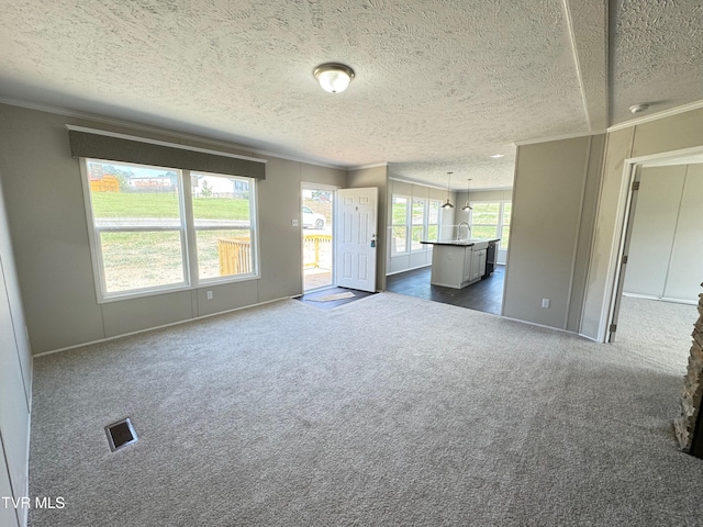 unfurnished living room featuring a textured ceiling, crown molding, sink, and dark carpet