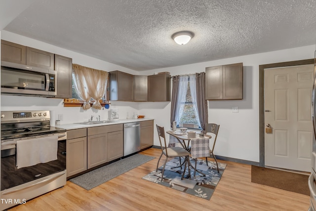 kitchen featuring stainless steel appliances, light hardwood / wood-style floors, a textured ceiling, and sink