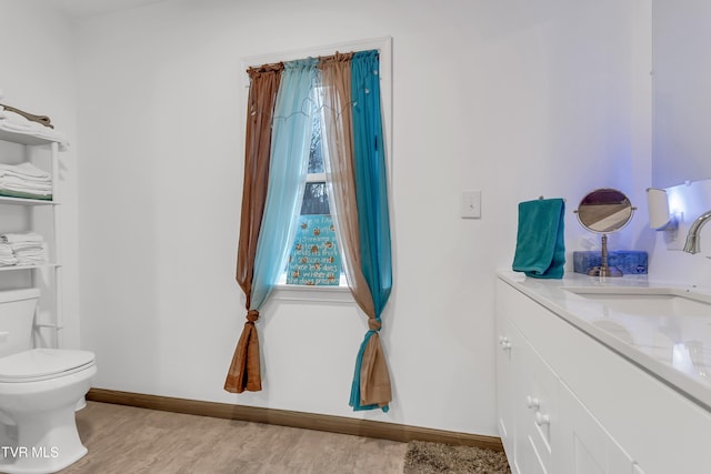 bathroom with toilet, vanity, wood-type flooring, and a healthy amount of sunlight