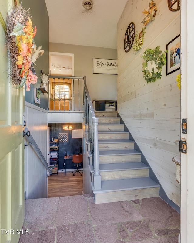 stairs featuring wooden walls and hardwood / wood-style floors