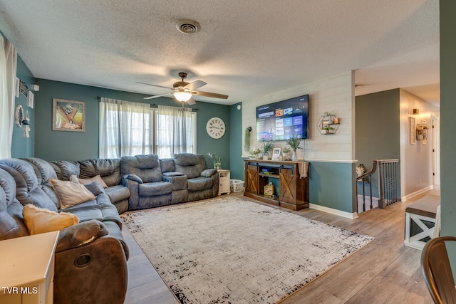 living room with light hardwood / wood-style floors, a textured ceiling, and ceiling fan