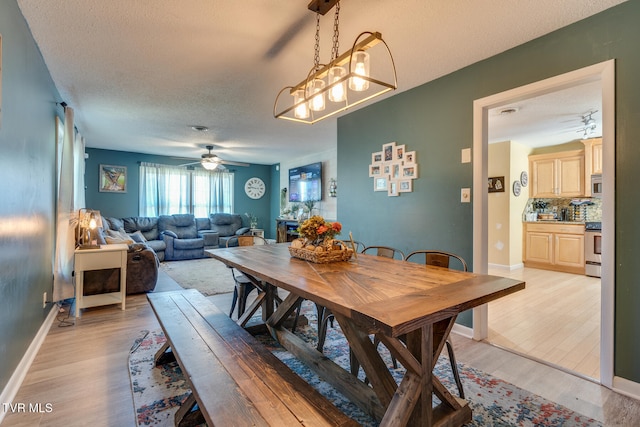 dining space with ceiling fan, a textured ceiling, and light hardwood / wood-style floors