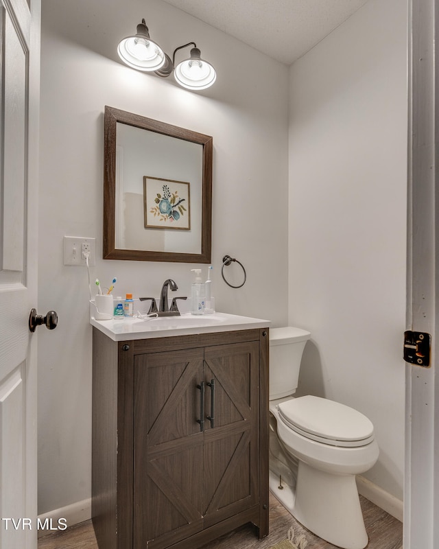 bathroom featuring wood-type flooring, toilet, and vanity