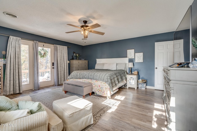 bedroom with a textured ceiling, access to outside, light hardwood / wood-style flooring, and ceiling fan