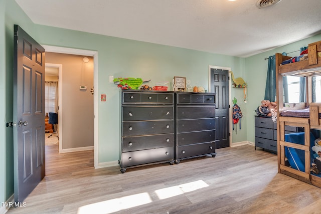 bedroom with a textured ceiling and light hardwood / wood-style floors