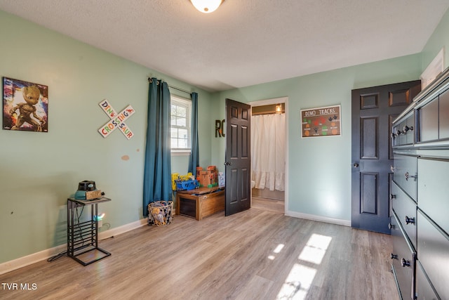 miscellaneous room with light hardwood / wood-style flooring and a textured ceiling