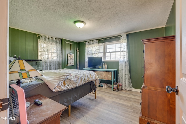 bedroom with a textured ceiling, light hardwood / wood-style flooring, and crown molding