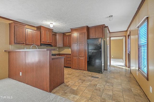 kitchen featuring ornamental molding, kitchen peninsula, a healthy amount of sunlight, and black refrigerator