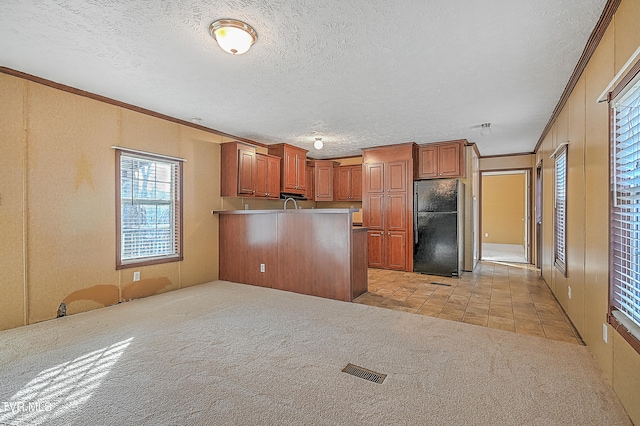 kitchen featuring black fridge, light colored carpet, kitchen peninsula, a textured ceiling, and ornamental molding