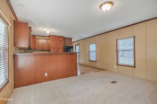 kitchen featuring black refrigerator, crown molding, kitchen peninsula, and light colored carpet