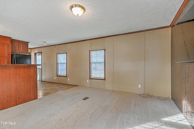 interior space featuring black refrigerator, a textured ceiling, crown molding, and light colored carpet