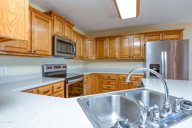 kitchen with a textured ceiling, stainless steel appliances, and sink