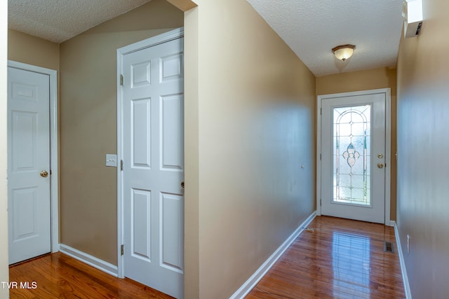 doorway with a textured ceiling and hardwood / wood-style flooring