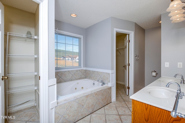 bathroom featuring vanity, tiled tub, tile patterned floors, and a textured ceiling