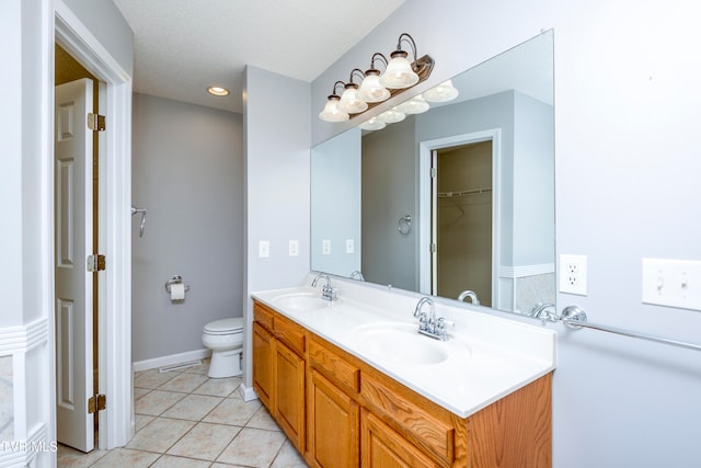 bathroom with toilet, vanity, and tile patterned floors