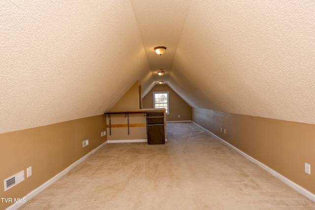 bonus room featuring vaulted ceiling, carpet, and a textured ceiling