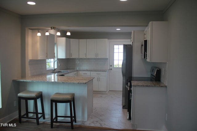 kitchen featuring a wealth of natural light, white cabinetry, sink, and appliances with stainless steel finishes