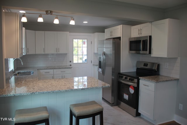 kitchen with a breakfast bar, white cabinets, sink, decorative light fixtures, and stainless steel appliances