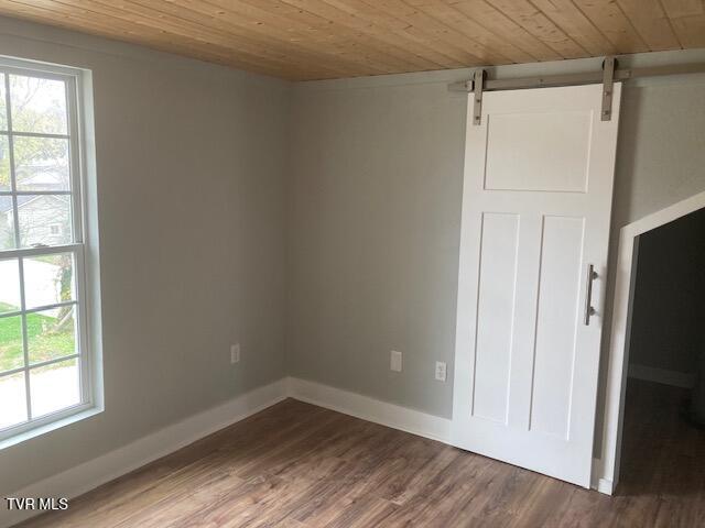 unfurnished room with a barn door, wood ceiling, and dark wood-type flooring