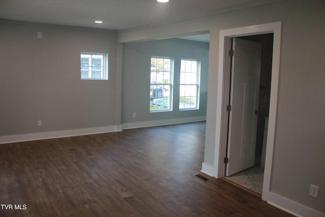 unfurnished room featuring dark wood-type flooring, crown molding, and a healthy amount of sunlight