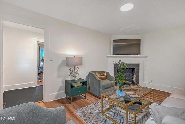 living room with wood-type flooring and a brick fireplace