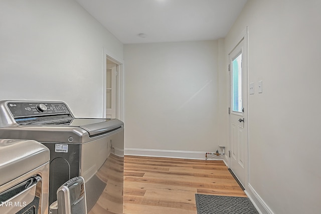 laundry room with separate washer and dryer and light hardwood / wood-style flooring