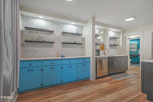 interior space with dishwasher, light wood-type flooring, blue cabinetry, and sink